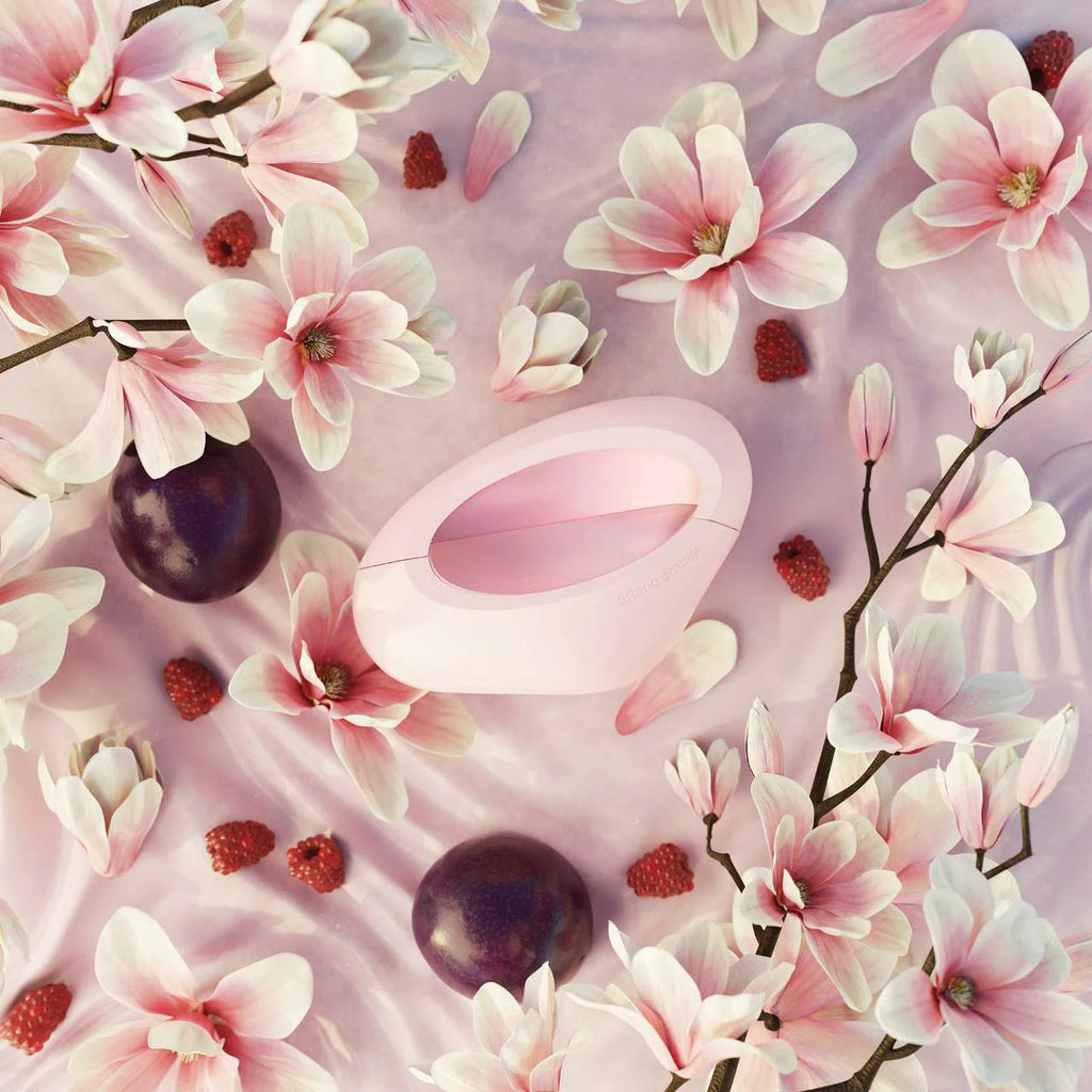 Pink electronic device surrounded by pink flowers and plums on a pink background