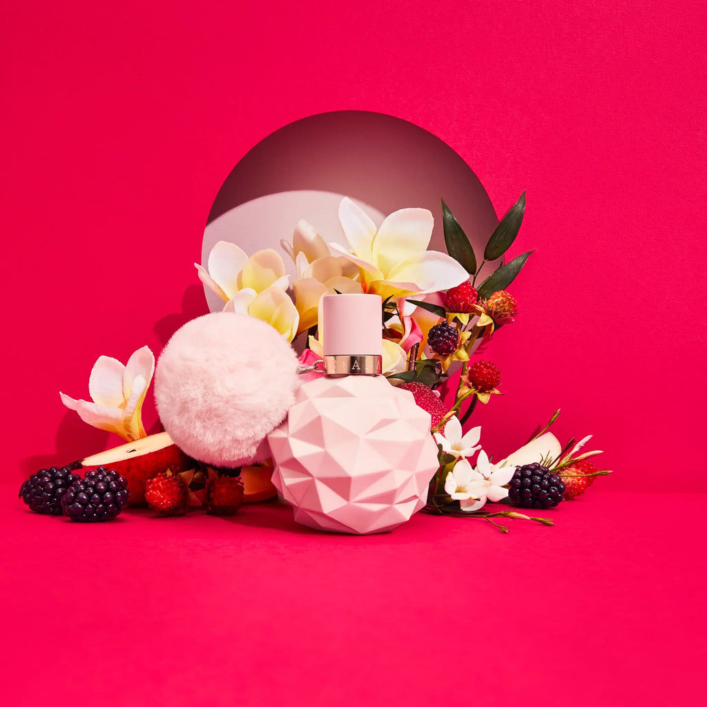 Pink perfume bottle with flowers and berries on a pink background