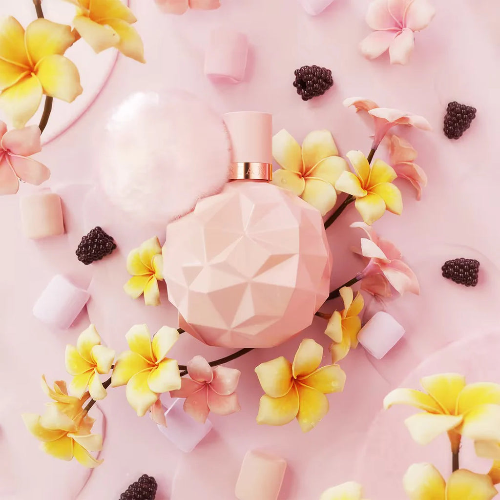 Pink perfume bottle surrounded by flowers and blackberries on a pink background