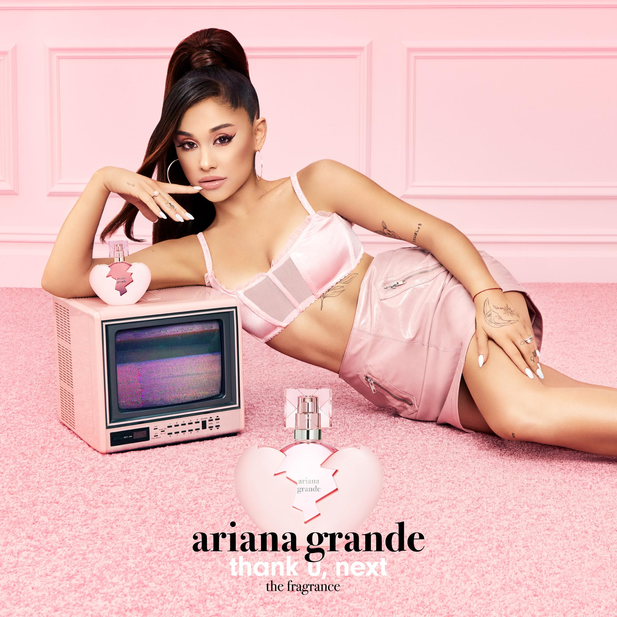 Ariana Grande in a promotional setting for her fragrance 'thank u, next' on a pink background.