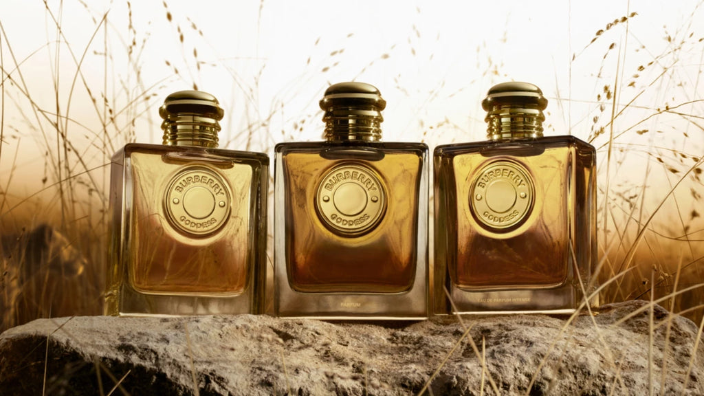 Three gold perfume bottles on a stone surface with a natural background